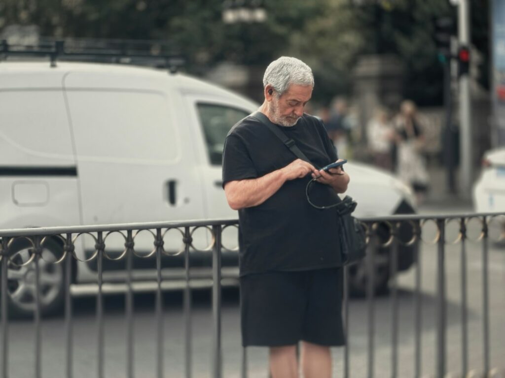 Senior man smiling while using his phone outdoors