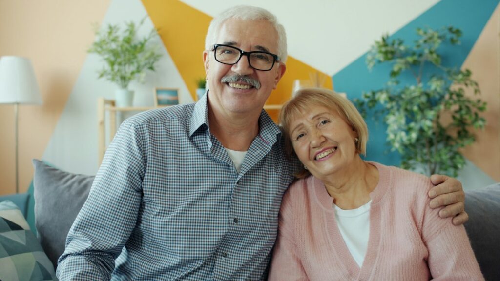 Cheerful retired couple embracing on couch at home