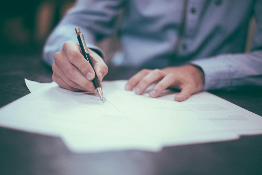 Hands signing legal paperwork